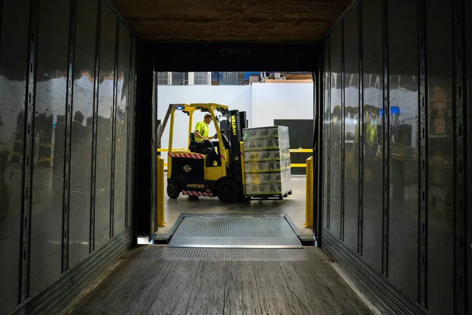 A forklift carrying a pallet towards a trailer at a loading dock